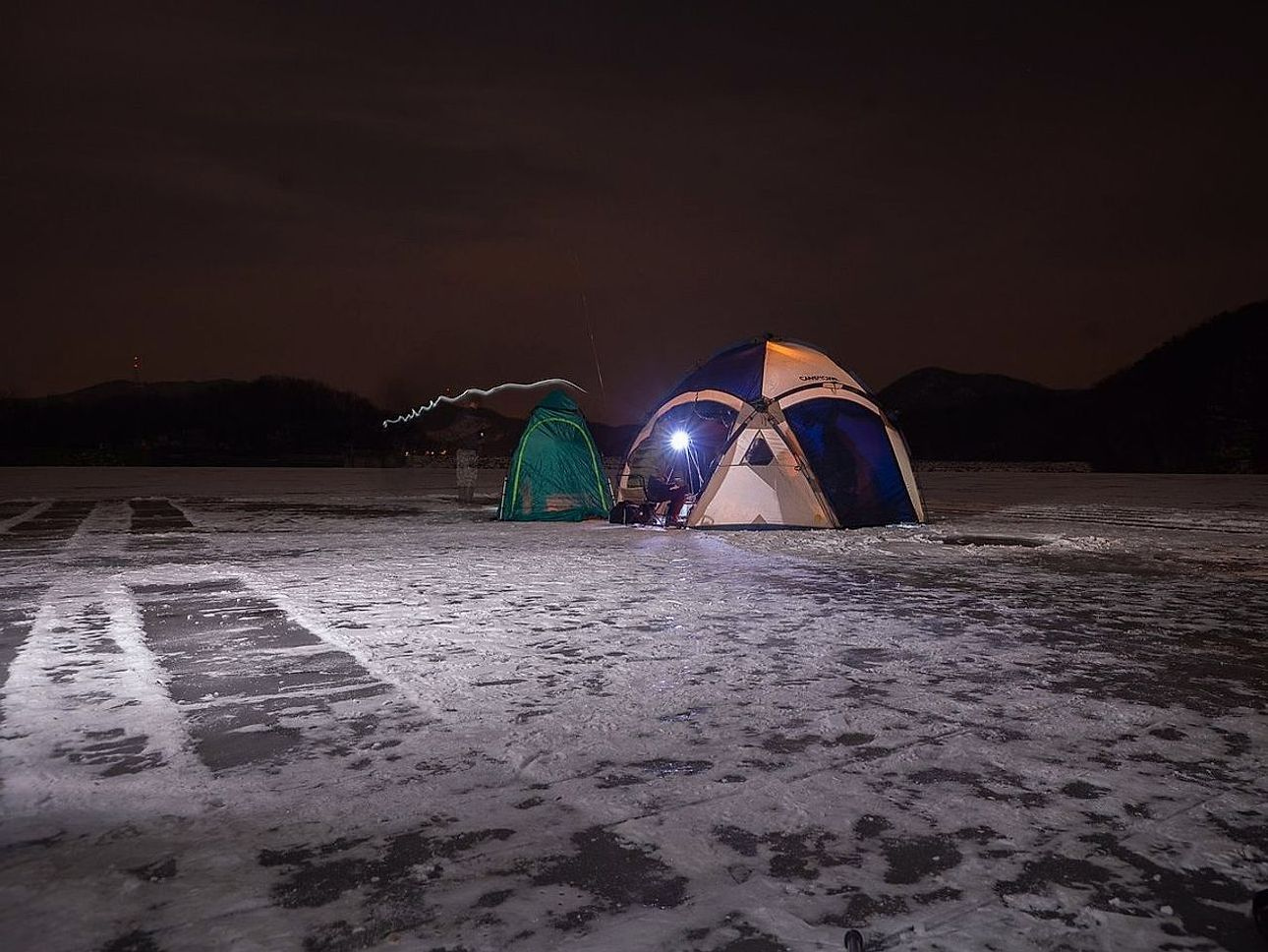 Paisagem aberta com picos nevados e lago sob o gelo à distância